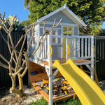 the Sunshine Shack cubby house with a slide - in the garden